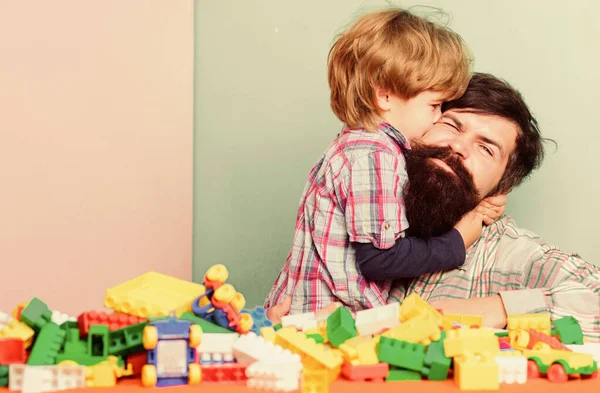 父と息子はレンガで楽しみを持っています。子供の発達と養育。髭を生やしたヒップスターとボーイが一緒に遊ぶ。幸せな子供時代プラスチックブロックのお父さんと子供のビルド。育児の概念。幸せな家族 — ストック写真