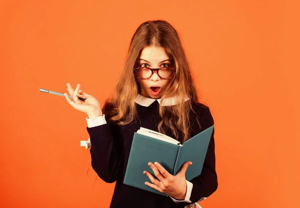 Creare e sorprendere. Studentessa sorpresa con penna e libro sfondo marrone. Il bambino tiene la bocca aperta di sorpresa. Bel look. Ragazza nerd. Scuola e istruzione. Concetto di sorpresa. Idea a sorpresa — Foto Stock