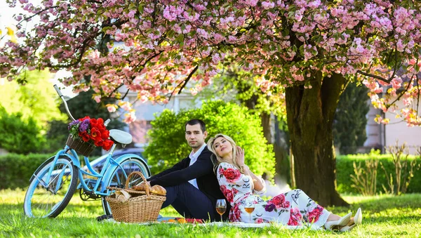 Happy loving couple relaxing in park with food. Romantic picnic with wine. Give uncommon, unique gifts spontaneously. Enjoying their perfect date. Couple in love picnic date. Spring weekend — Stock Photo, Image