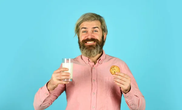 Het concept van gezond eten. Biologische landbouwproducten voor ontbijt of lunch. melk en koekjes. gelukkige boer eet koekjesdessert. bebaarde man drinkt nuttige melk met gebak — Stockfoto