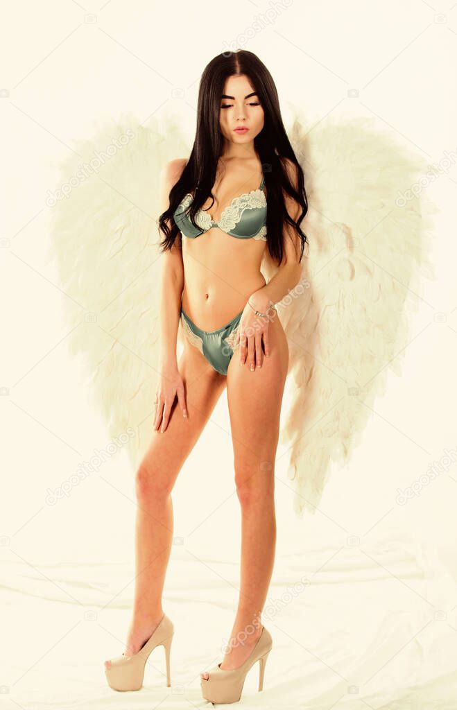 Divine and bohemian. Delicate sensual woman posing with angel wings. Girl wear luxury lingerie and angel wings accessory. Fashion model. Erotic angel. Desirable and tempting lady. Impressive purity