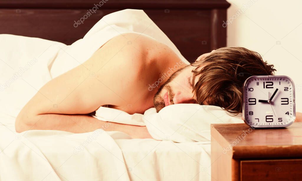 Young man stretching while waking up in the morning. Picture showing young man stretching in bed. Young man waking up.