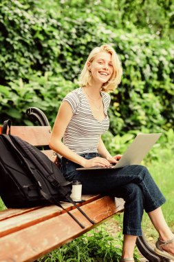 Modern öğrenci hayatı. İnternette sörf yapmak. Laptop kahve fincanı ve sırt çantası olan sevimli bir kız öğrenci. Kadın öğrenci defterle çalışıyor. Araştırmayı öğren. Dışarıda ders çalış. Sıradan bir öğrenci.