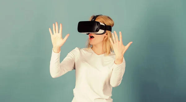 Young woman using a virtual reality headset with conceptual network lines. Amazed young woman touching the air during the VR experience. Beautiful woman wearing virtual reality goggles in studio.