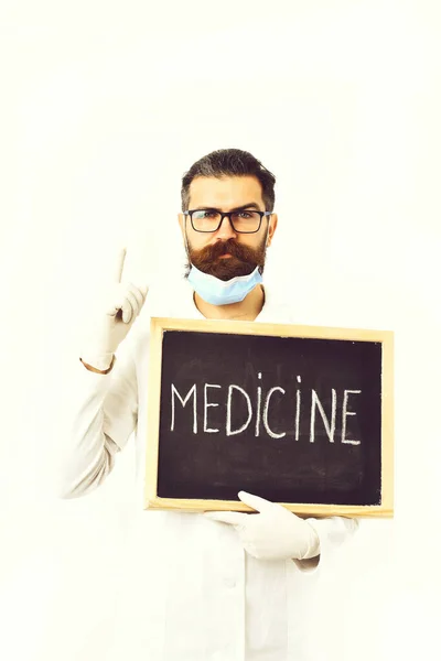 Médico caucasiano barbudo segurando seringa e papelão com inscrição em Medicina — Fotografia de Stock