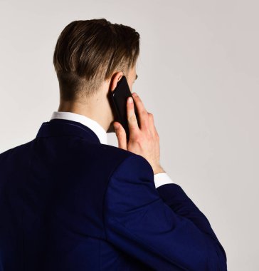 Gri arka planda cep telefonuyla konuşan adam..