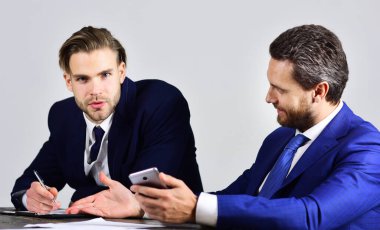 İş adamlarının elinde akıllı telefon, kalem ve defter var.