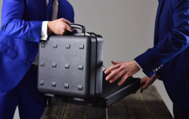 Erkek eller ahşap masada açık siyah çantayı tutar.