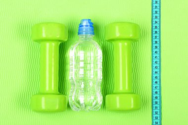 İki plastik halter ve şişe. Diyet ve vücut geliştirme kavramı