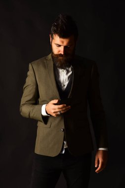 Sakallı bir işadamının cep telefonu var. Takım elbiseli adam.