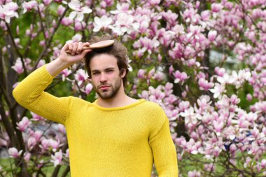 Parkta tomurcuklanan ağaçlarla saçlarını tarayan maço.