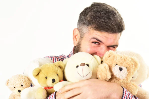 Macho com barba abraça muitos ursos de pelúcia e brinquedos de pelúcia . — Fotografia de Stock