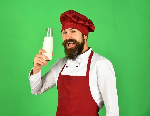 Cook med glada ansikte i vinröd uniform håller mjölk. — Stockfoto