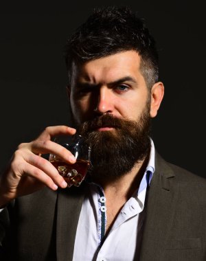 Ciddi yüzlü bir adam bir bardak alkolle kadeh kaldırıyor.