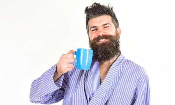 Человек с бородой и усами держит кружку кофе, изолированного на белом. Утренний кофе. Мачо в халате пьет чай или кофе с улыбающимся лицом . — стоковое фото