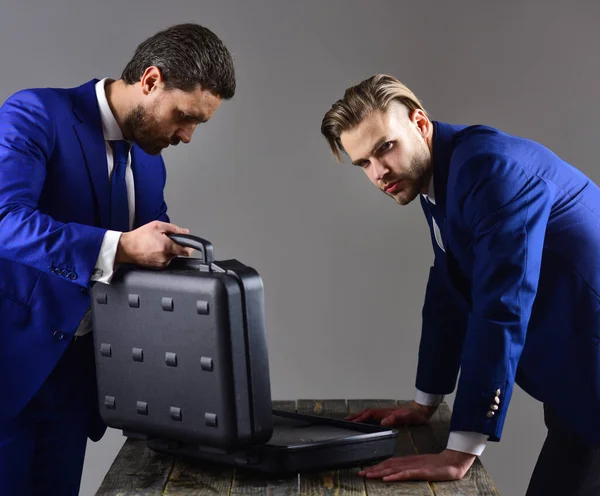 Geschäftsleute blicken in geöffnete Aktentasche vor dunklem Hintergrund. — Stockfoto