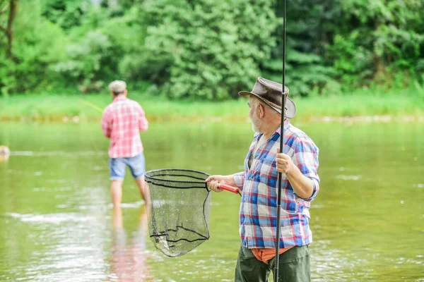 Mutlu emeklilik. Baba oğul balık tutuyor. Erkek arkadaşlığı. Aile bağı. Yaz haftasonu. Olta kamışlı iki balıkçı, seçici bir odak noktası. Emekli olgun erkek balıkçısı. hobi ve spor aktivitesi — Stok fotoğraf
