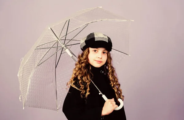 Miúda menina feliz segurar guarda-chuva transparente. Desfrute de tempo chuvoso com roupas adequadas. Acessórios impermeáveis tornam o dia chuvoso divertido. Temporada de Outono. Aproveite o conceito de chuva. Tendência de moda infantil. Amor dias chuvosos — Fotografia de Stock