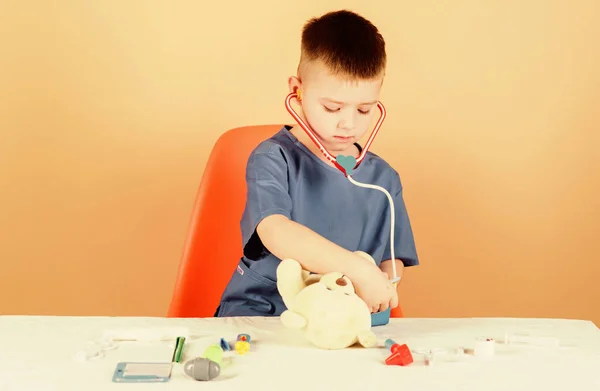 Concepto de medicina. Procedimientos médicos para el oso de peluche. Educación médica. Niño lindo niño futuro médico carrera. Salud. El pequeño doctor está ocupado sentándose en la mesa con herramientas médicas. Examen médico — Foto de Stock