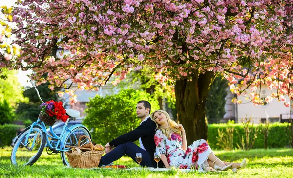 Lycklig tillsammans. Blommor symbol för romantik och tillgivenhet. Njuter av deras perfekta dejt. Par koppla av i parken med cykel. Romantisk picknick med vin. Ett par i kärlekspicknick. Vårhelg — Stockfoto