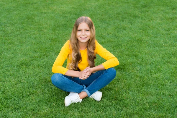 Teen girl after hairdresser. relax on green grass. spring leisure time. happy childhood. kid with stylish hair. cheerful smile. happy little girl has long curly hair. kid beauty and fashion — Stock Photo, Image