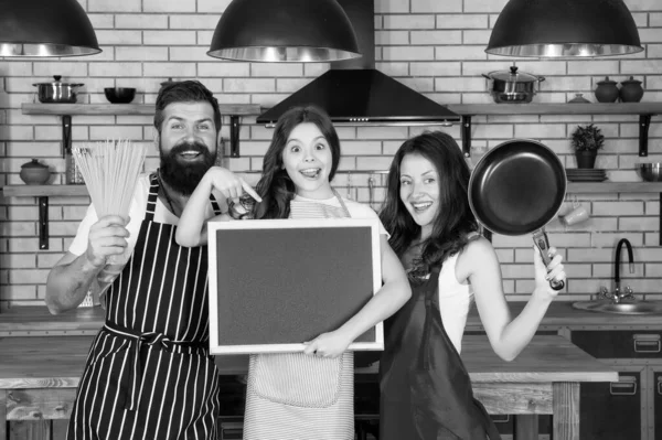 Recipe of perfect family dinner. Mother and father with little girl holding chalkboard copy space. Little girl with parents cooking. Family day. Happy family in kitchen. Pleasant time together