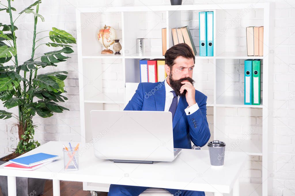 Business thinking. Serious businessman sit at office desk. Bearded men think over serious business. Project manager with serious look. Work and career. Professional life. Serious and thoughtful