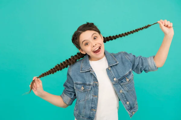 Quando tenho o cabelo comprido, vou ao salão. Criança feliz segurar cabelos longos fundo azul. Menina sorrir com penteado trançado. Salão de cabeleireiro. Salão de beleza. Produtos de cabeleireiro de salão. Shampoo e condicionador — Fotografia de Stock