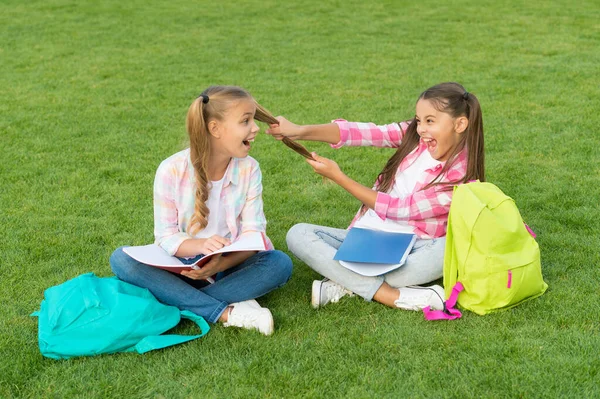 C'est l'heure de se détendre. s'amuser sur l'herbe verte. deux petits enfants avec sac à dos. petite fille jouer et étudier sur la pause scolaire. heureux jour des enfants. fraternité et concept de famille. jour de connaissance est venu — Photo