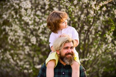 Çok mutluyum. Yakışıklı bir baba ve tatlı bir oğlu var. Çiçek ve doğanın tadını çıkarın. Mutlu aile günleri. Bahar geliyor. Eğlenmene bak. Aşk konsepti. Neşeli baba parkta çocuğuyla oynuyor.