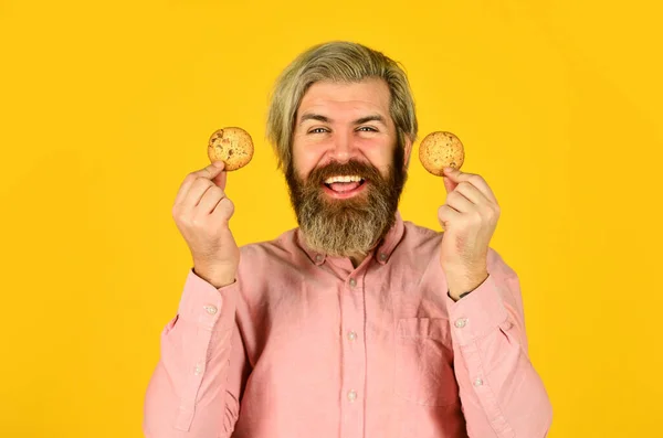 Aufgeregter Mann mit Keksen in der Hand. bärtige Hipster halten Keks in der Hand. Kalorienreich. Konzept der schädlichen Lebensmittel. Gebäck und Dessert. Bäckereiwerbung. Mann auf Diät. Mann mit Keks in der Hand — Stockfoto