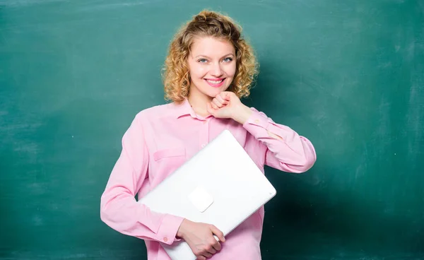 Software for teachers. School lecturer with notebook. Woman cheerful teacher hold laptop stand near chalkboard. School education concept. Modern education. Teaching informatics. Back to school