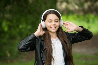 Müzik kulağı var. Mutlu çocuk dışarıda kulaklık takıyor. Küçük kız kulaklıkla müzik dinler. Rahatlatıcı kulaklıklar. Kulak koruyucu cihazlar. İşitme koruması. Yeni teknoloji. Modern hayat