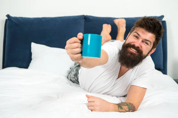 Profitez de votre tasse de café tous les jours. Happy hipster profiter du café au lit. L'homme barbu donne une tasse chaude. Café au lit. Chambre d'hôtes. Détendez-vous et profitez. Plaisir et joie. Bonjour. Bonjour. Profitez de votre journée — Photo