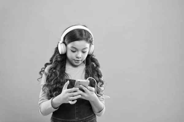 オンラインエンターテイメント。無料音楽アプリ。無料で聞いてください。音楽アカウントのサブスクリプションを取得します。小さな女の子の子供は音楽現代のヘッドフォンやスマートフォンを聞きます。音楽のコンセプトを楽しむ。完璧なサウンドをお楽しみください — ストック写真