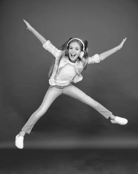 Childhood happiness. happy kid listen music. freedom and success. Little girl in earphones. reach her dream. fly up in air. going crazy. excited small girl wear headset. dance with favorite song — Stock Photo, Image