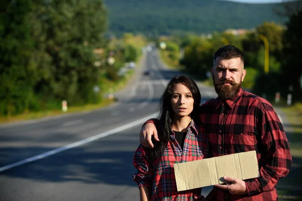 Man and woman try to stop car with cardboard sign. — Stock Photo, Image