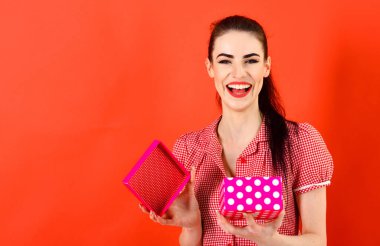 Noel hediyesi tutan mutlu genç bir kadın. Kırmızı arkaplanda izole