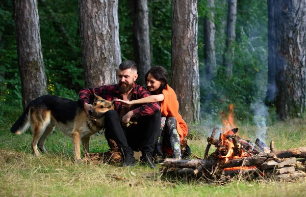 Man spela, klapp tyska herde hund nära brasa, natur bakgrund. — Stockfoto
