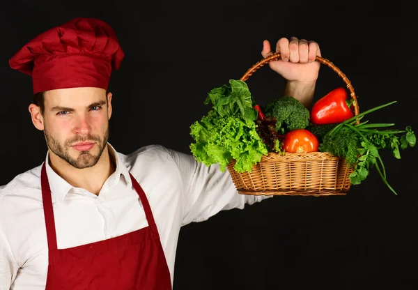 Koch mit ernstem Gesicht hält frische Zutaten bereit. Konzept der Bioküche. — Stockfoto