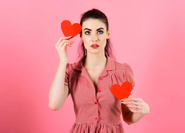 En flicka som håller röda hjärtan isolerade på rosa bakgrund. — Stockfoto