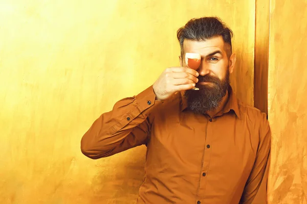 Brutal caucasiano hipster segurando tiro alcoólico sobre fundo textura dourada — Fotografia de Stock