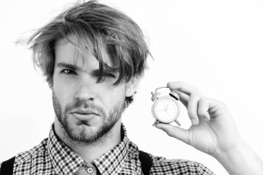 Ciddi yüzlü ve sakallı bir adam pembe çalar saati tutuyor.