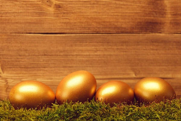 Tradiční velikonoční zlatá vejce na dřevěném pozadí — Stock fotografie
