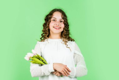 Çiçekler onun için. Uluslararası Çocuk Günü. Anneler Günü konsepti. Kıvırcık saçlı neşeli küçük kız. Çocuk için lale çiçeği. Çocuk lale çiçeklerini tutuyor. Bahar buketi. Mutlu kadınlar günü.