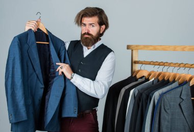 Man in custom tailored suit presenting tailored tuxedo. Man clothing in boutique. tailor in his workshop. Handsome bearded fashion man in classical costume suit. Looking for design inspiration clipart