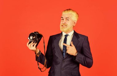 Olgun bir adam sakal ve saç boyadı. Profesyonel fotoğrafçı fotoğraf çeker. Erkek güzeli. Berber salonunun yakalanması. Klasik kamera. Kendine güvenen iş adamı retro kamerayı tutuyor