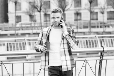 Akıllı telefon ve şehir kullanan bir adam. Adam akıllı telefondan konuşuyor. Sokakta cep telefonu olan modern bir adamın açık hava portresi. Çalışıyorum. Girişimci cep telefonu kullanıyor. Kahvaltı yapıyor.