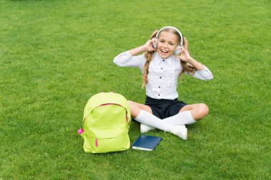 Eğitim en iyi dosttur. Eğitim konsepti. Online öğrenmenin sıradan bir günü. Kızım müzik dinle. Okul bahçesinde kitabı olan mutlu anaokulu kızı. Okula dönüyorum. Çalışkan çocuk kulaklık takıyor