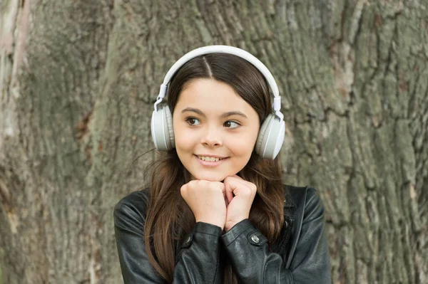 Bara musik som betyder nåt. Glad tjej lyssnar på musik utomhus. Små barn bär hörlurar som spelar musik. Konsert och musikföreställning. Ny teknik. Det moderna livet. Kul och underhållning — Stockfoto